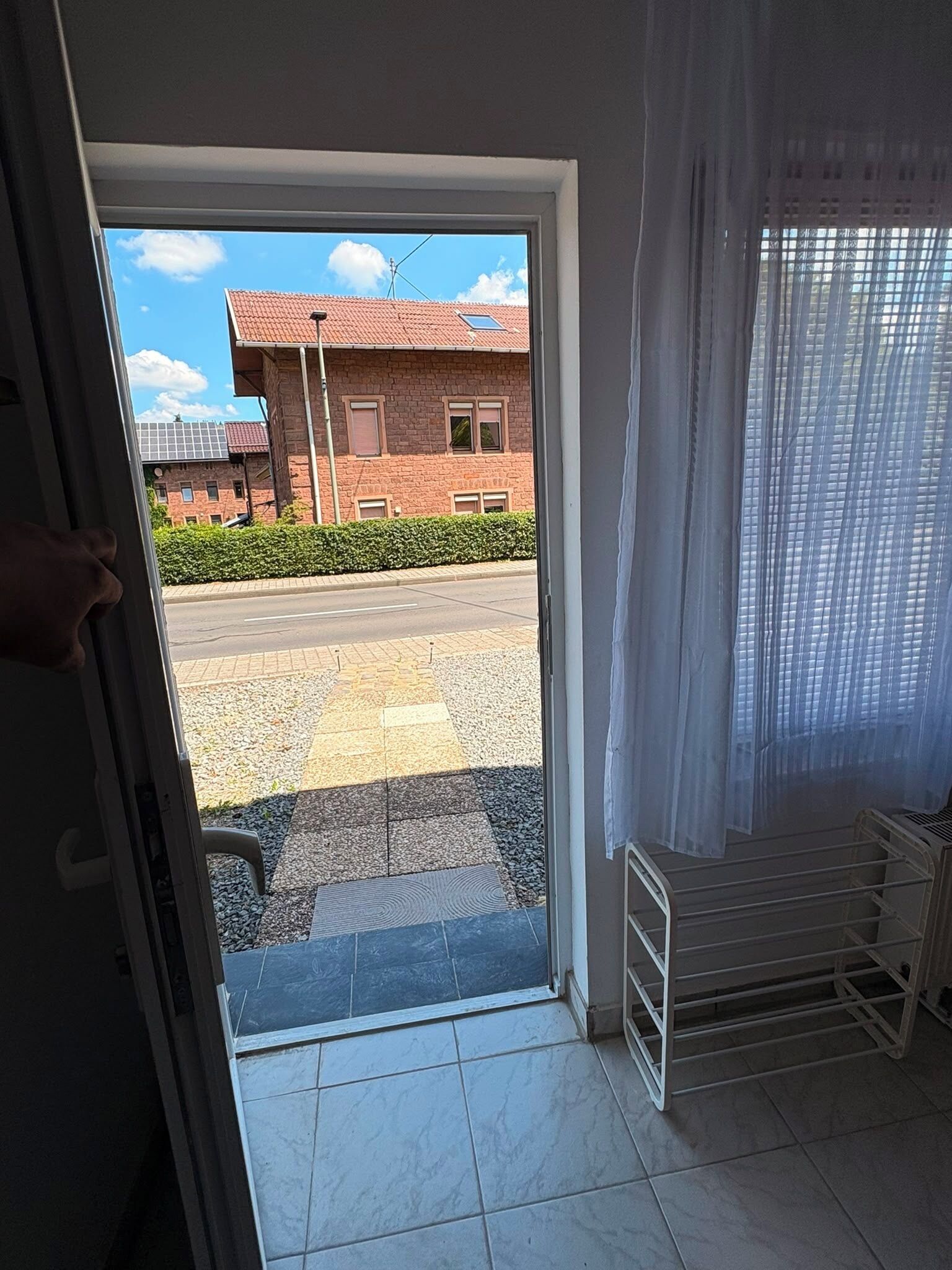 A room with a door leading to a street view, a tiled floor, and a metal radiator.