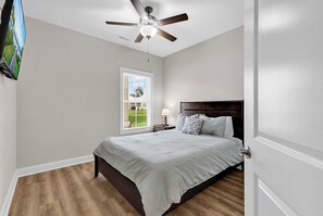 Ein Schlafzimmer mit Bett, Deckenventilator, Fenster und Nachttisch.