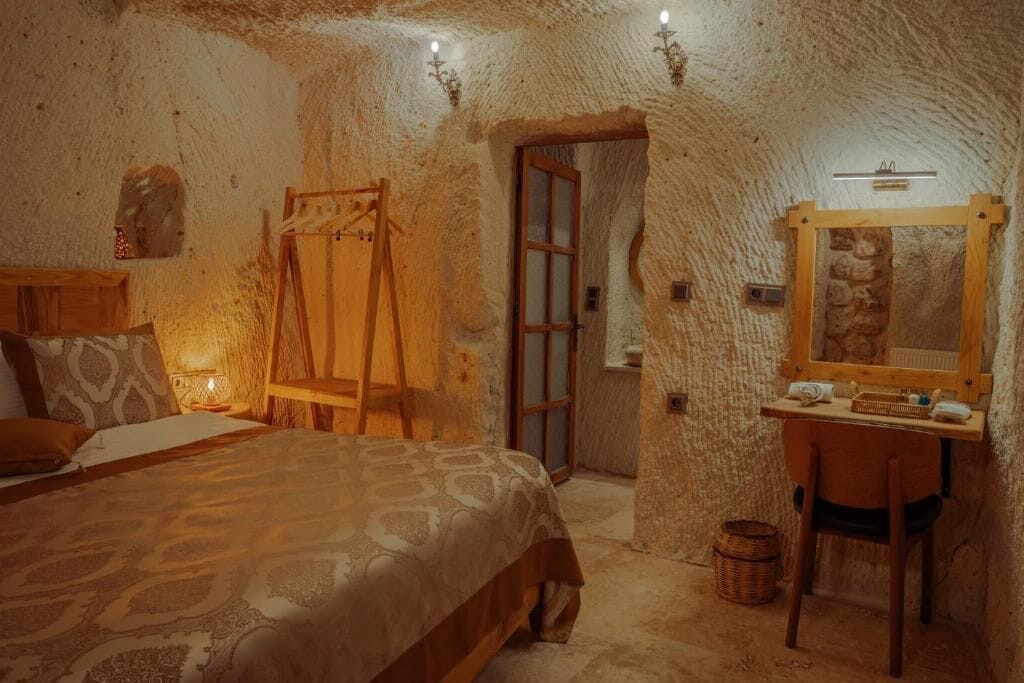 Ein rustikales Zimmer mit einem Bett, einem Holztisch, einem Spiegel und einer Tür.