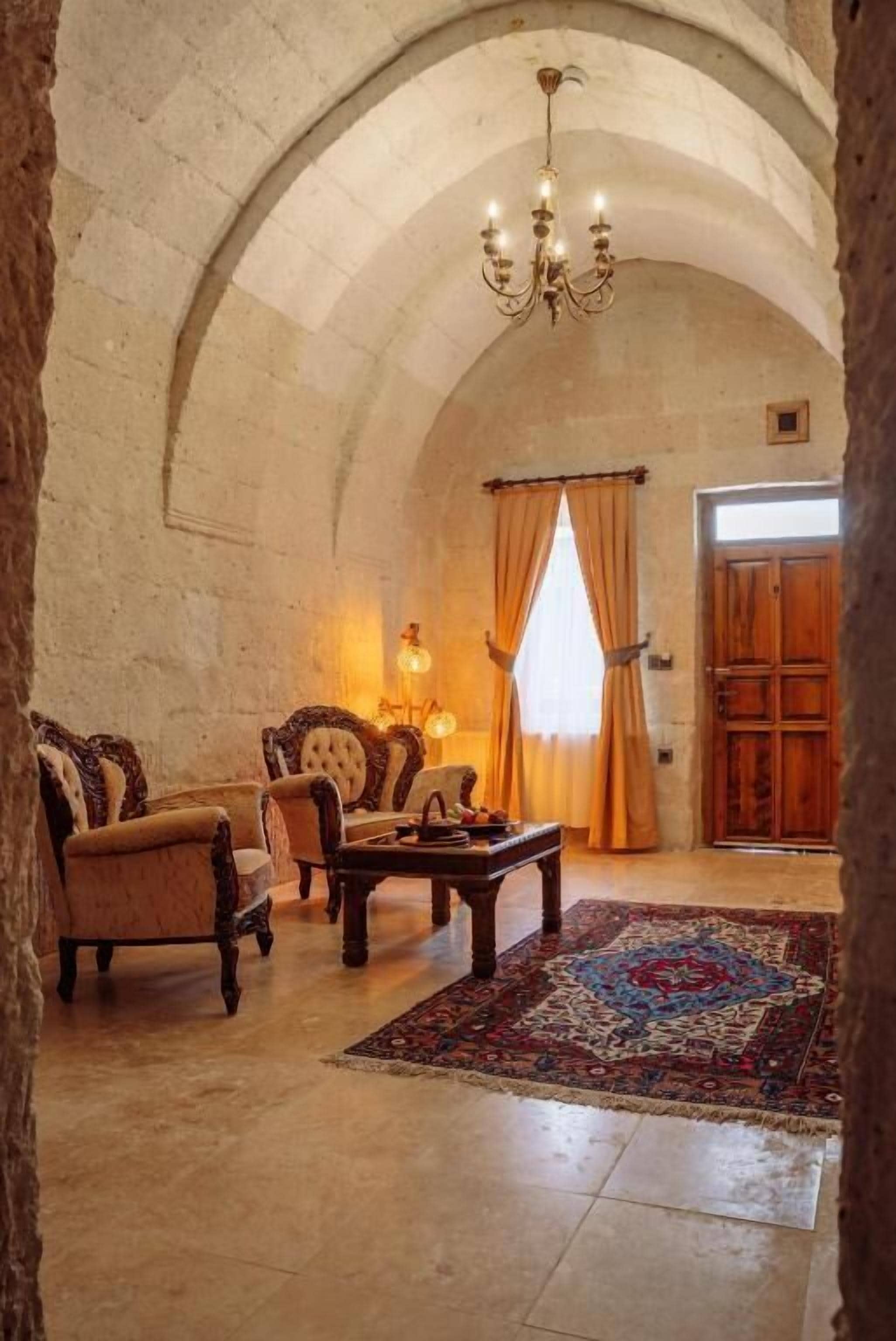 Ein Zimmer mit gewölbter Decke, einem Kristalllüster, einem gemusterten Teppich und traditionellen Möbeln.