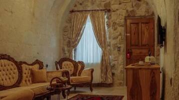 A room with a stone archway, a chandelier, a sofa, a wooden cabinet, and a patterned rug.