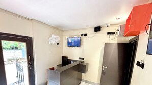 Un baño moderno con piso de mármol, un lavamanos, un espejo y un televisor montado en la pared.