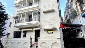 Un hotel de varios pisos con balcones, un cartel y una entrada con portón.