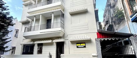 A multi-story hotel with balconies, a signboard, and a gated entrance.
