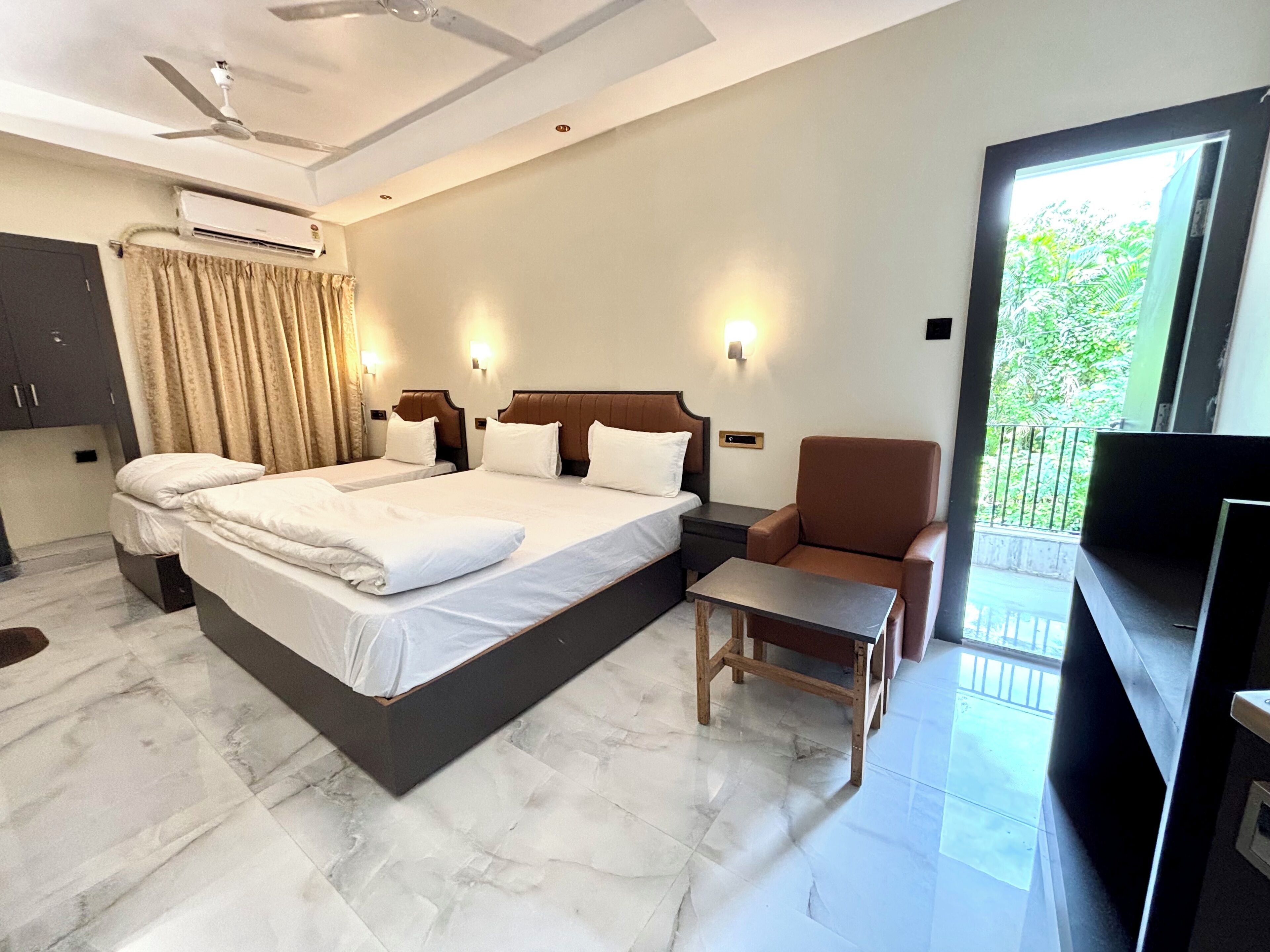 A hotel room with a large bed, a chair, a small table, and a TV.