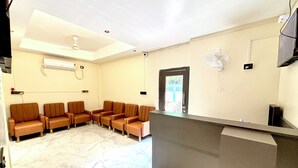A reception area with a marble floor, a reception desk, and a row of brown chairs. - Hotel Fivetel (Barasat)