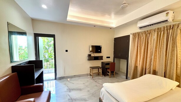 A hotel room with a bed, a desk, a chair, a television, and an air conditioning unit. - Hotel Fivetel (Barasat)
