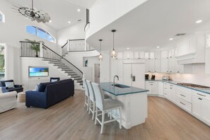 A spacious living area with a sofa, chairs, a TV, and a staircase leading to an upper level. - Waterfront Marco Island Home w/ Pool, Spa & Kayaks (Marco Island)