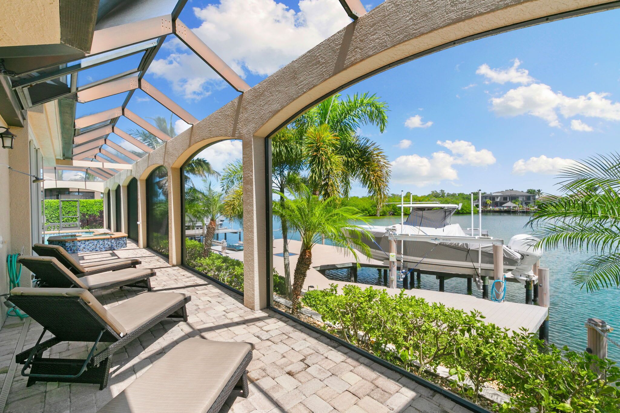 A sunlit outdoor lounge area with lounge chairs and a view of a marina.