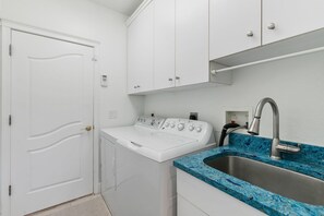 A laundry room with a washing machine, a sink with a blue marble countertop, and white cabinets. - Waterfront Marco Island Home w/ Pool, Spa & Kayaks (Marco Island)