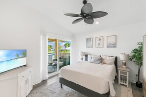 A bedroom with a bed, a television, a ceiling fan, and a view of the outside. - Waterfront Marco Island Home w/ Pool, Spa & Kayaks (Marco Island)