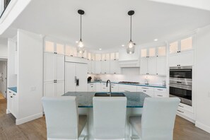 A modern kitchen with white cabinetry, a central island with seating, and built-in appliances. - Waterfront Marco Island Home w/ Pool, Spa & Kayaks (Marco Island)