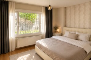 A bedroom with a bed, a nightstand, a lamp, a window with curtains, and a radiator. - Cozy Bright 1Bd Near Bosphorus (Istanbul)