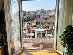 A balcony with a table and chairs, potted plants, and a view of a residential area. - Cozy Bright 1Bd Near Bosphorus (Istanbul)