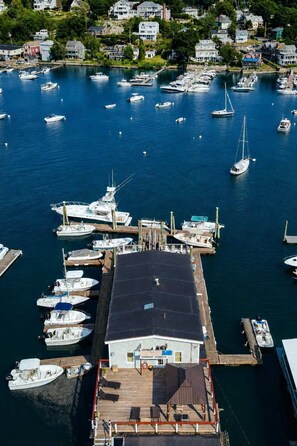 A marina with multiple boats docked, a wooden pier, and a building with a flat roof.