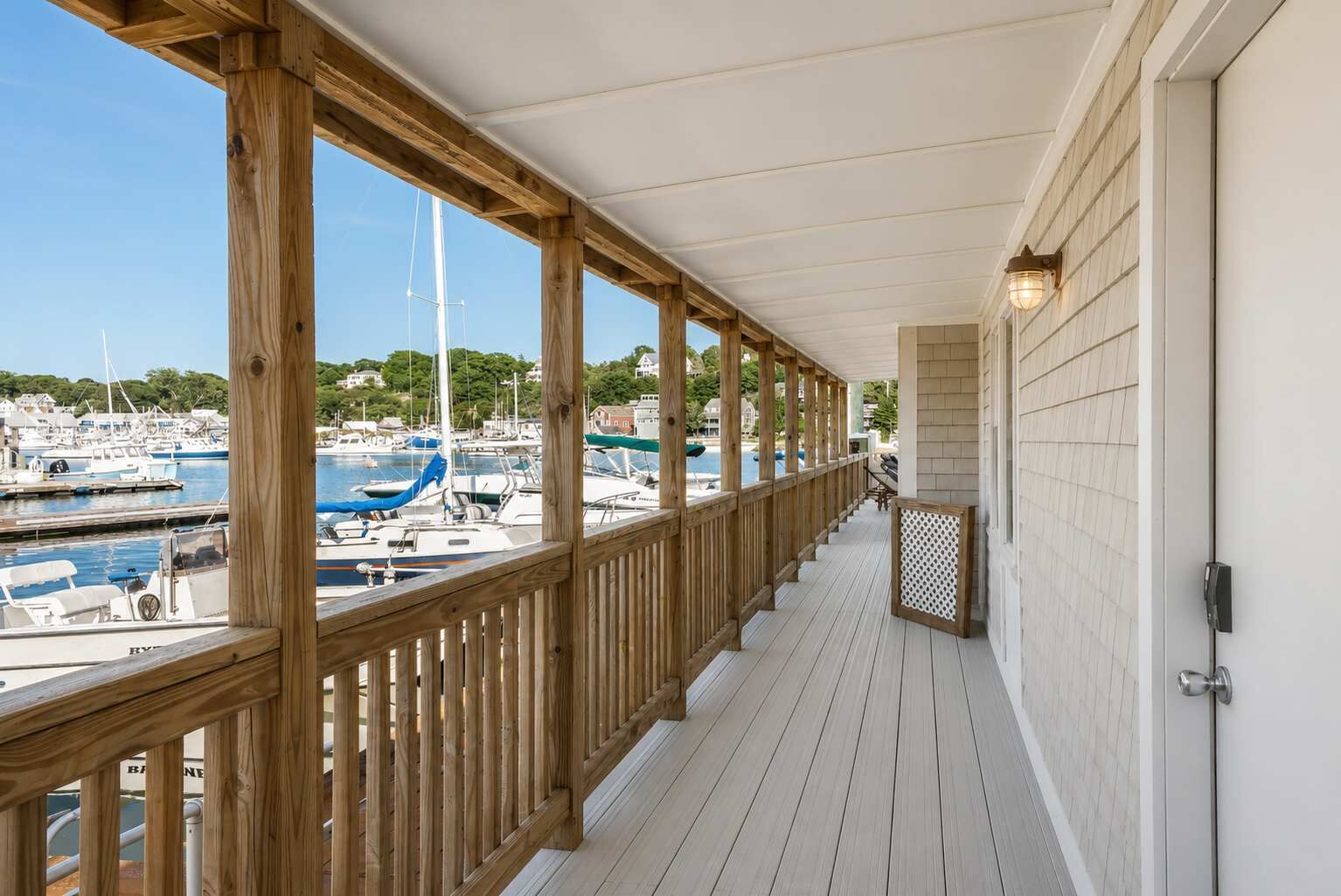 A wooden deck with a view of a marina and houses in the background.