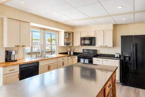 A modern kitchen with a large island, stainless steel appliances, and a view of the marina.