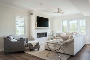 A modern living room with a grey sofa, a grey armchair, a coffee table, and a fireplace. - Stay at Good Harbor Beach (Gloucester)