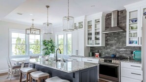 A modern kitchen with a central island, stainless steel appliances, and a stone backsplash. - Stay at Good Harbor Beach (Gloucester)