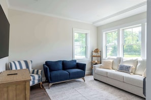 Ein Wohnzimmer mit einem blauen Sofa, einem gestreiften Sessel, einem beigen Sofa und einem Holztisch.
