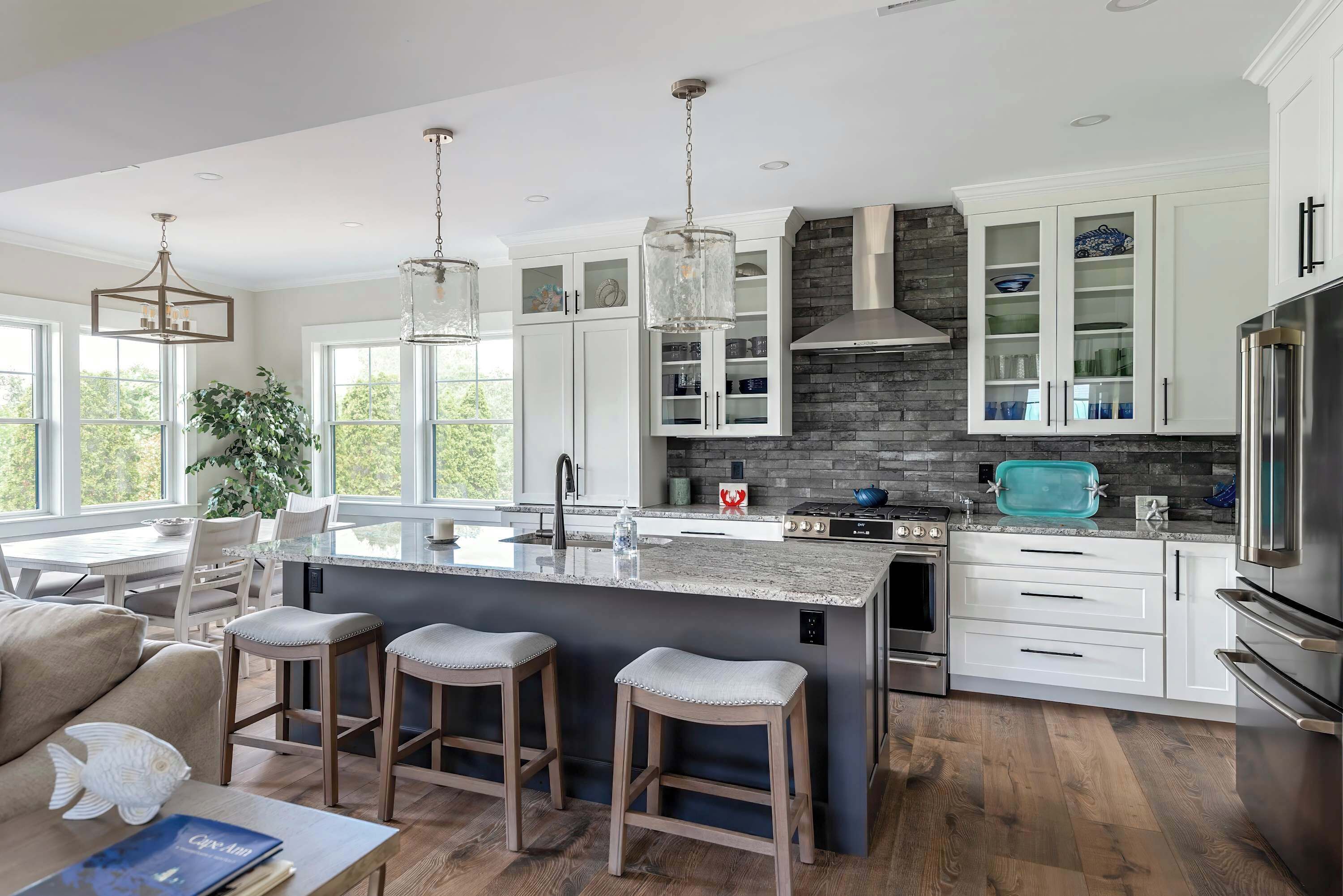 A modern kitchen with a central island, white cabinetry, and a stone backsplash.