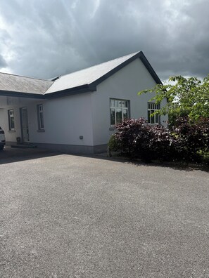 A building with a white exterior, a sloped roof, and a paved driveway. - Modern 2-Bed Escape, Cashel, Aherlow & Galtees (TA)