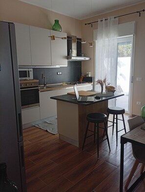 A modern kitchen with a central island, bar stools, and a dining table. - Don Turi Etna (Zafferana Etnea)
