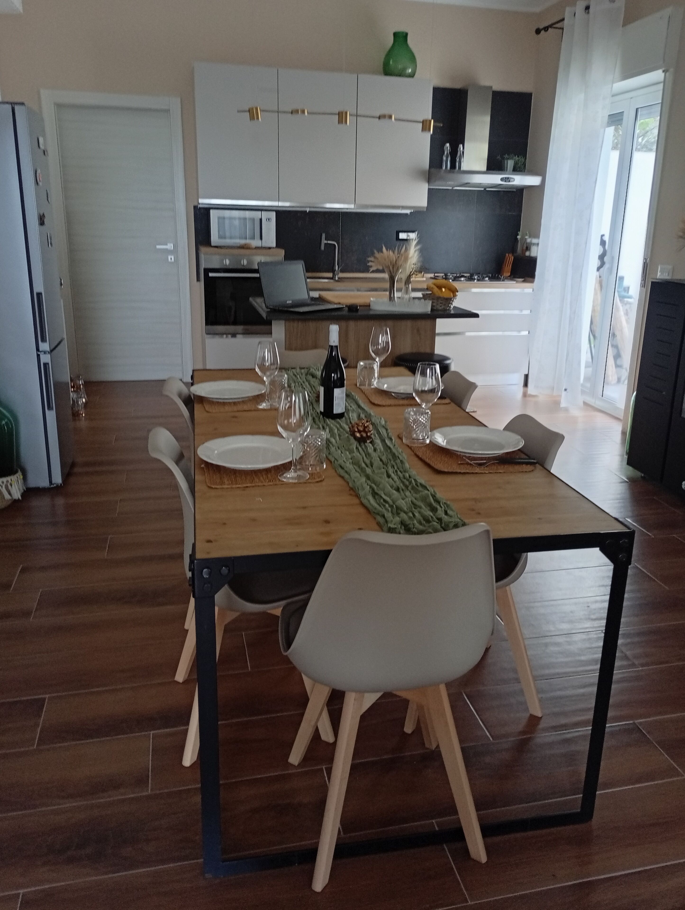 A modern dining area with a wooden table set for four, surrounded by chairs.
