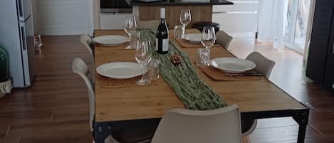 A modern dining area with a wooden table set for four, surrounded by chairs.