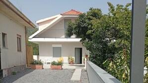 En bostadsfastighet med en grusuppfart, en balkong och krukväxter.