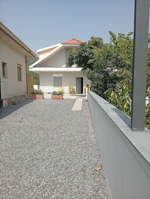 A residential property with a gravel driveway, a balcony, and potted plants. - Don Turi Etna (Zafferana Etnea)