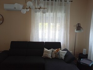 A living room with a dark sofa, a lamp, and a window with sheer curtains. - Don Turi Etna (Zafferana Etnea)