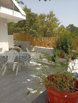 An outdoor patio area with a table and chairs, a potted plant, and a wooden fence. - Don Turi Etna (Zafferana Etnea)