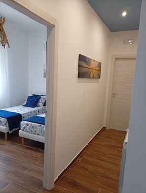 A bedroom with two beds, a painting on the wall, and a wooden floor. - Don Turi Etna (Zafferana Etnea)