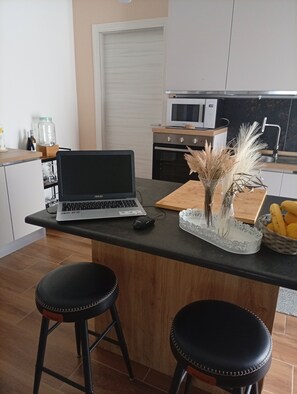 Una cocina moderna con una computadora portátil sobre una encimera, un microondas y un lavamanos.
