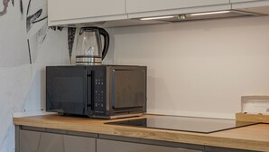 Una cocina con microondas, cafetera y una caja de cápsulas Nespresso.