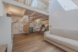 Ein modernes Interieur mit einer Holztreppe, einem Essbereich und einem Sofa.