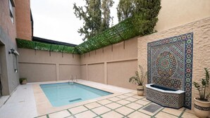 A swimming pool with a tiled deck, a bench, and a decorative wall. - Beautiful, quiet house in Marrakech, 7 bedrooms, pool, and live-in cook (Marrakech)