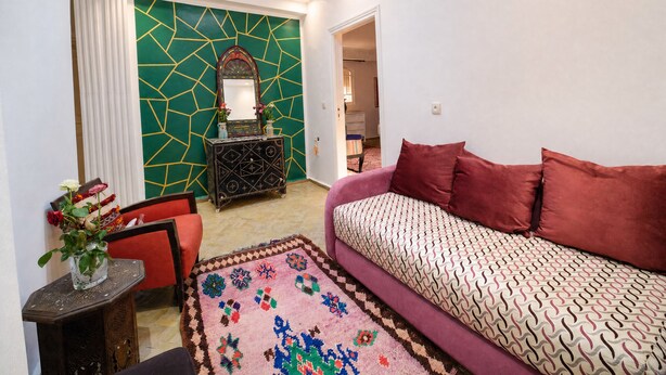 A room with a sofa, a patterned rug, a decorative mirror, and a wall with geometric patterns. - Beautiful, quiet house in Marrakech, 7 bedrooms, pool, and live-in cook (Marrakech)