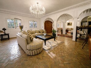 Ein geräumiges Wohnzimmer mit einem großen Ecksofa, einem Glastisch und einer Kronleuchter.