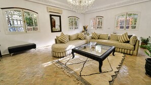 A spacious living room with a large sofa set, a glass coffee table, and a chandelier. - Beautiful, quiet house in Marrakech, 7 bedrooms, pool, and live-in cook (Marrakech)