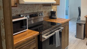 A modern kitchen with wooden cabinets, a stainless steel oven, and a microwave.