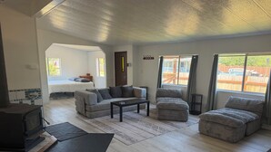 A spacious living room with a sofa, ottoman, and a television.