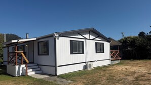 A single-story mobile home with a porch, a small staircase, and a fenced yard.