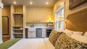 A compact hotel room with a bed, a small kitchenette, and a shower area.