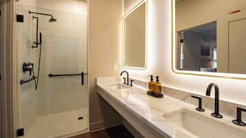 Ein modernes Badezimmer mit einer gläsernen Duschkabine, einem Waschtisch mit zwei Becken und einem großen Spiegel.