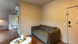 Une pièce avec un canapé gris, une table basse blanche et une porte dotée d’une serrure.