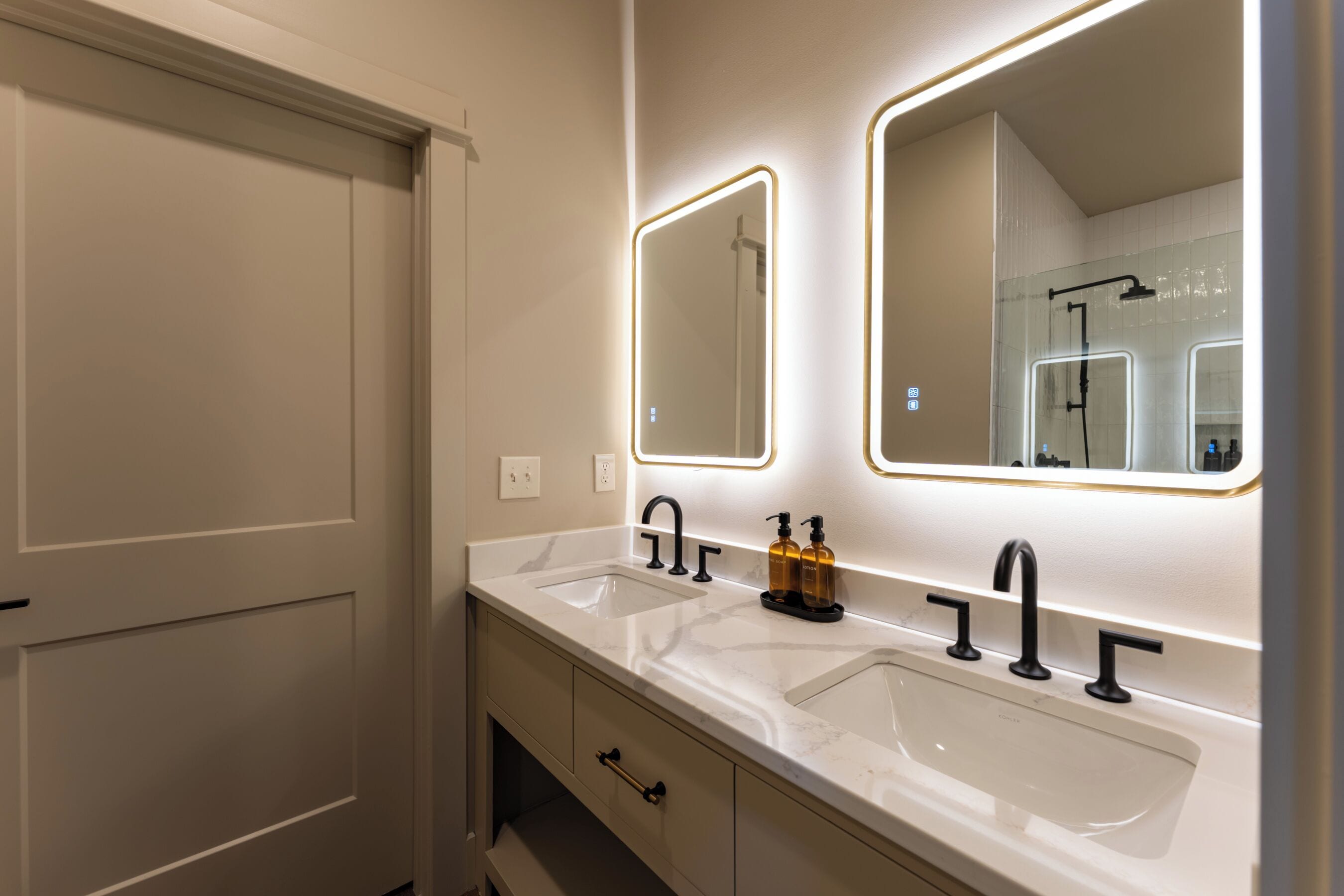 Een badkamer met twee wasbakken, een spiegel en een douche.