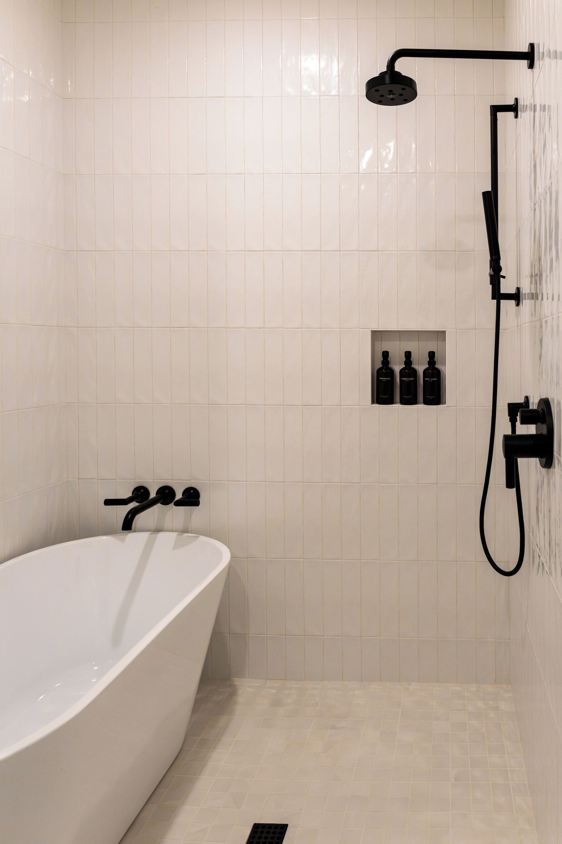 A bathroom with a freestanding bathtub, a handheld showerhead, and a wall-mounted faucet.