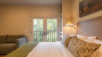 Una habitación de hotel con una cama, un sofá, un cuadro y vistas a través de una puerta.